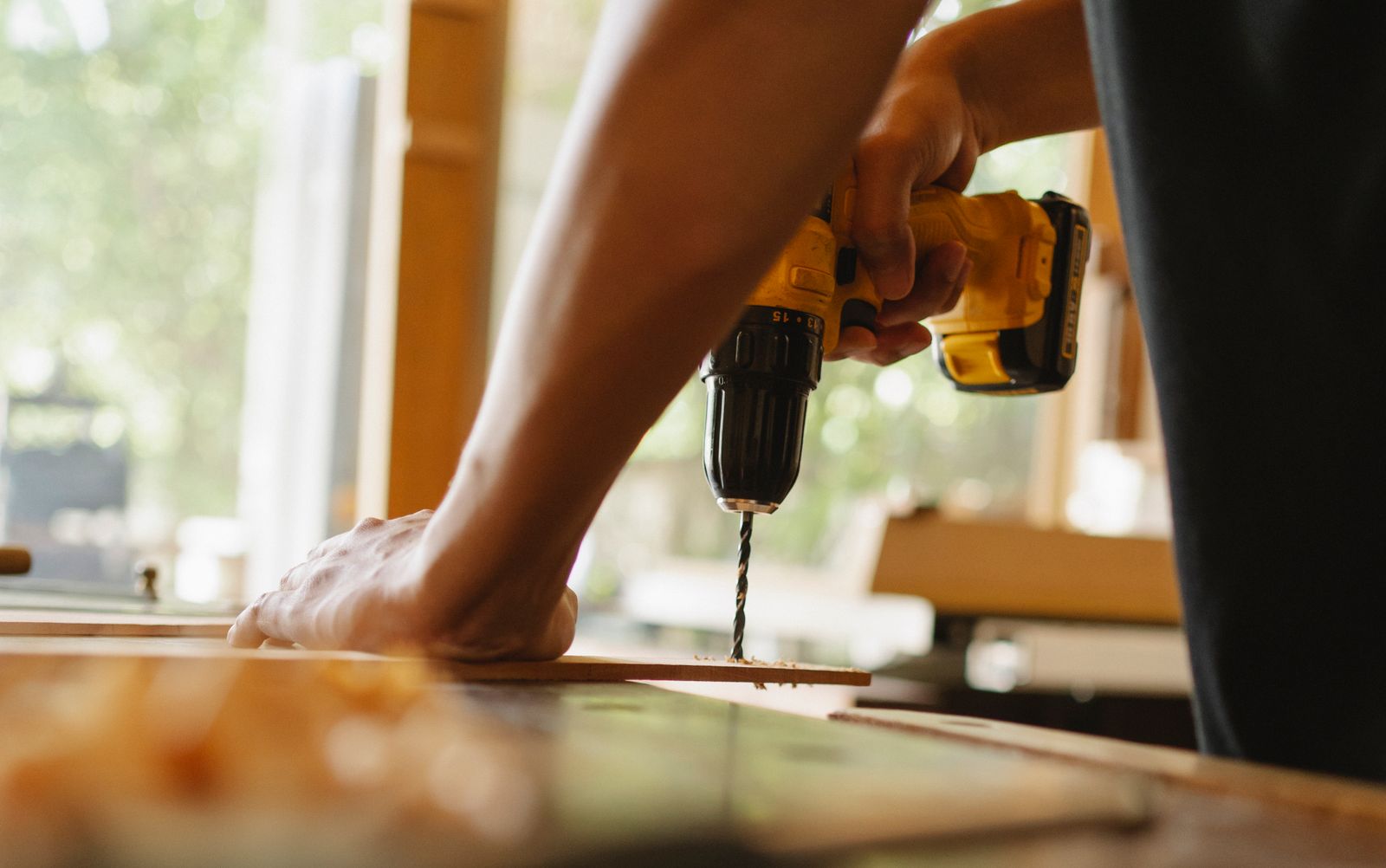 Menuisier perçant une planche de bois dans l'atelier